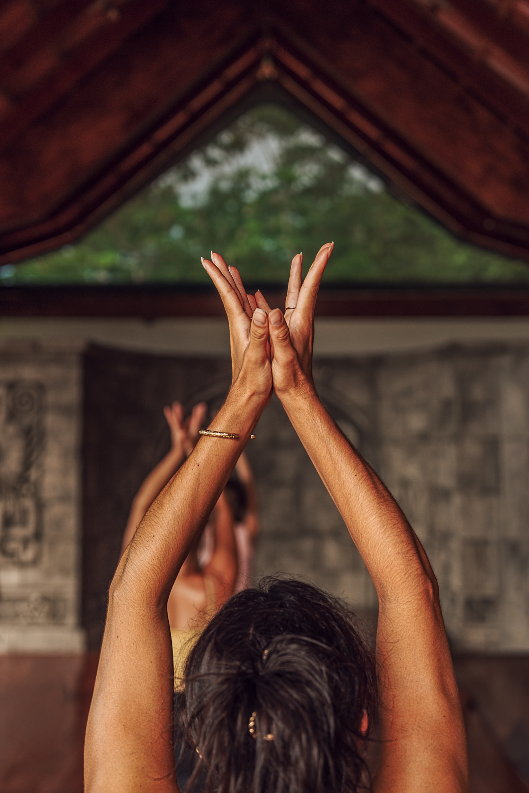 A retreat guest practices morning vinyasa on Anamaya's open-air yoga deck overlooking the lush jungle in Montezuma, Costa Rica.