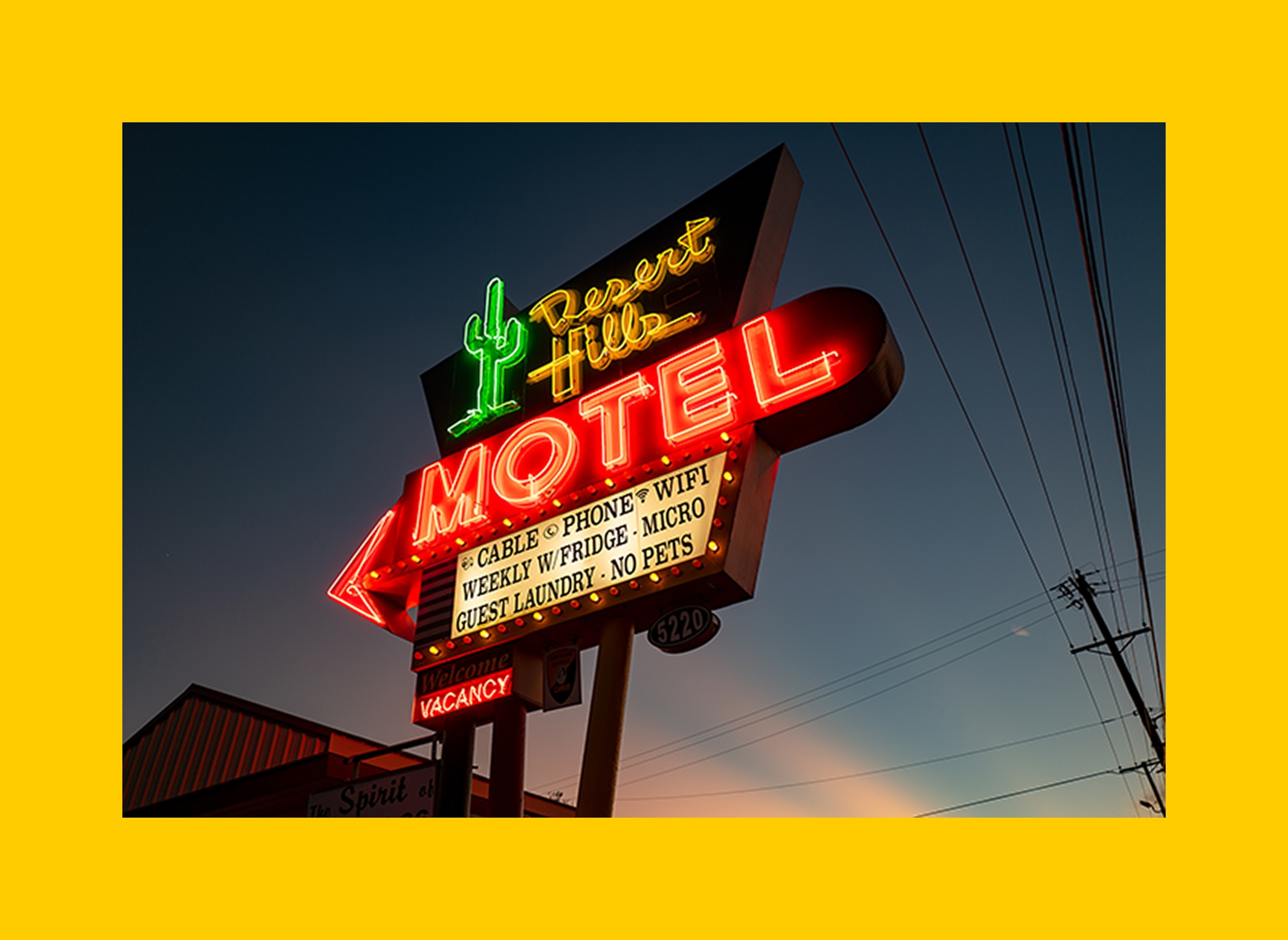 A photograph of the Desert Hills Motel on Route 66 sign, with its neon cactus sign glowing like a beacon from the past.