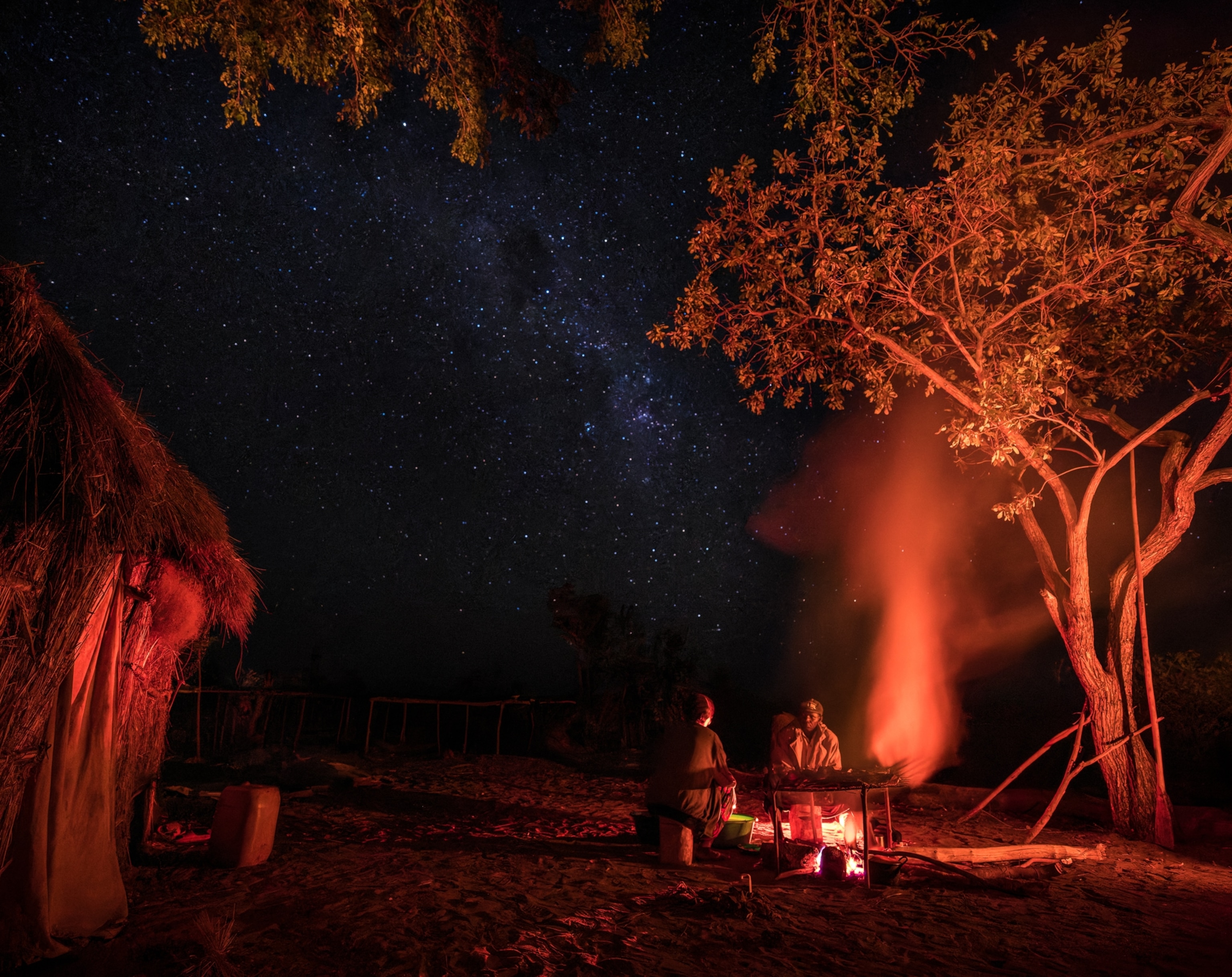 Two men sitting by campfire.