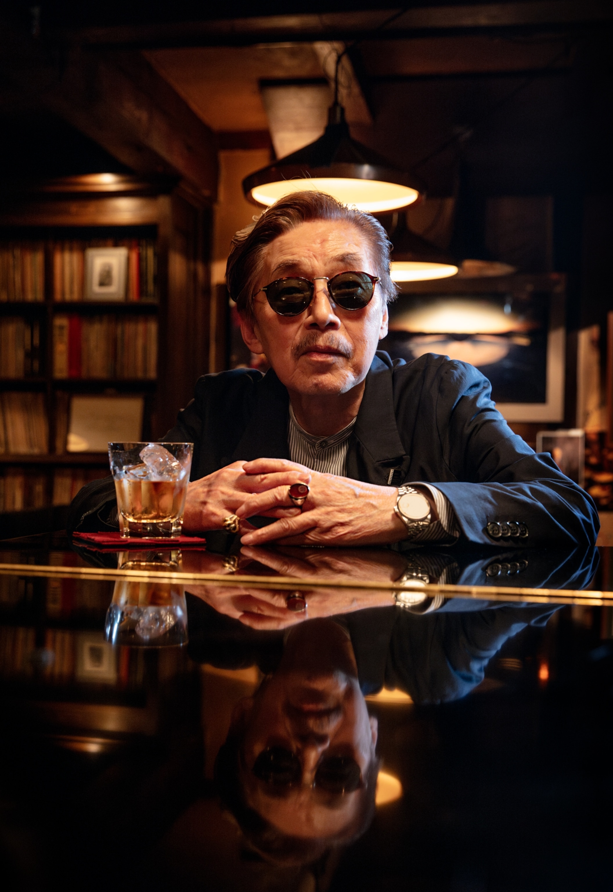 Man in dark sunglasses having a drink at the piano.