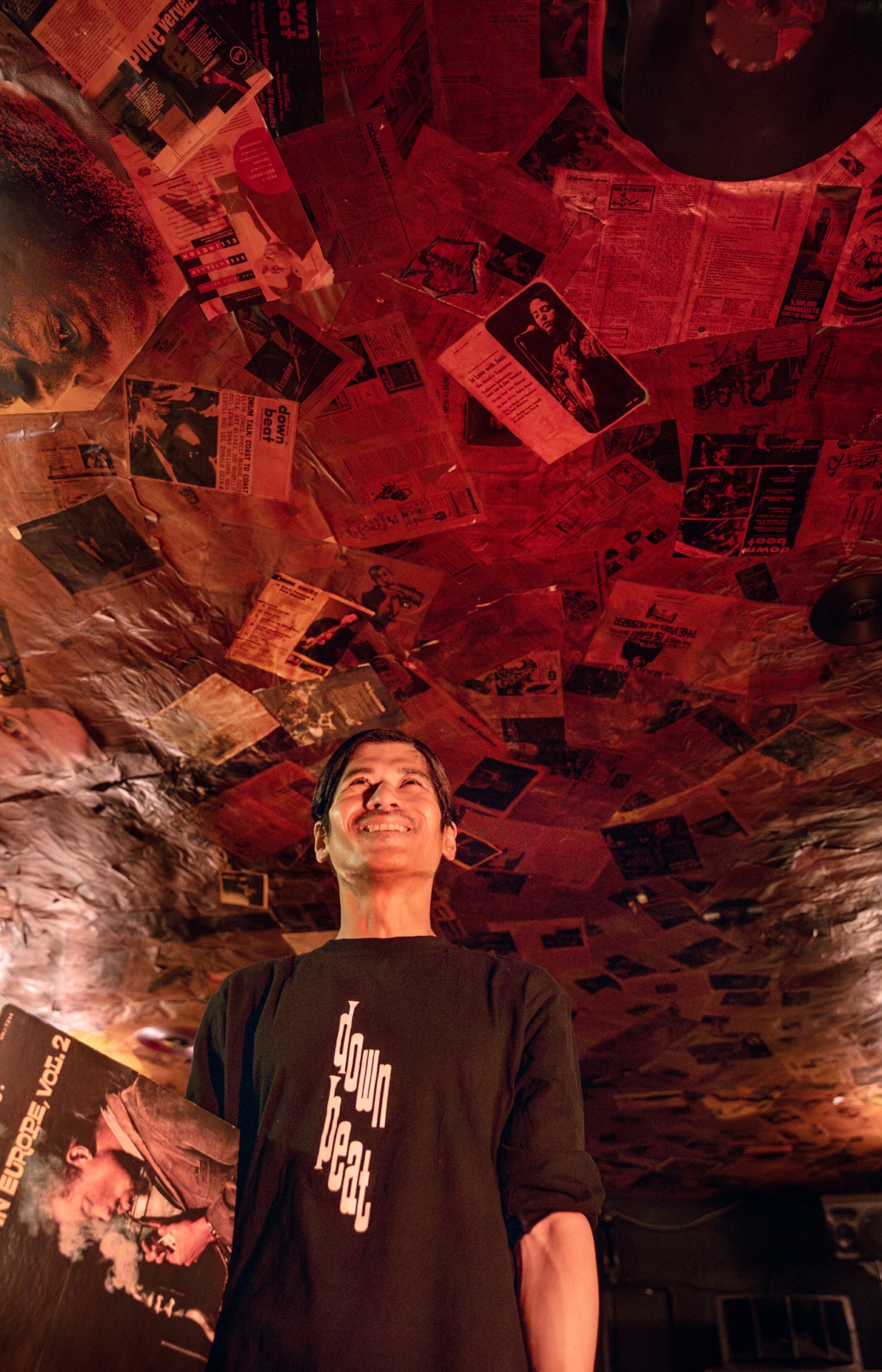 Man smiling under ceiling covered with newspapers and magazines clipping.