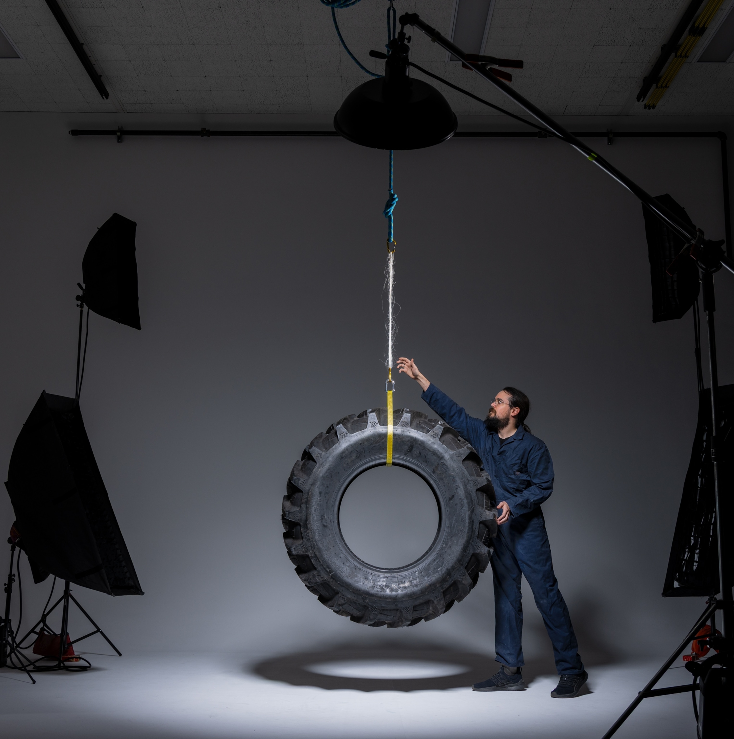 Man standing next to tractor tire suspended on silk loop.