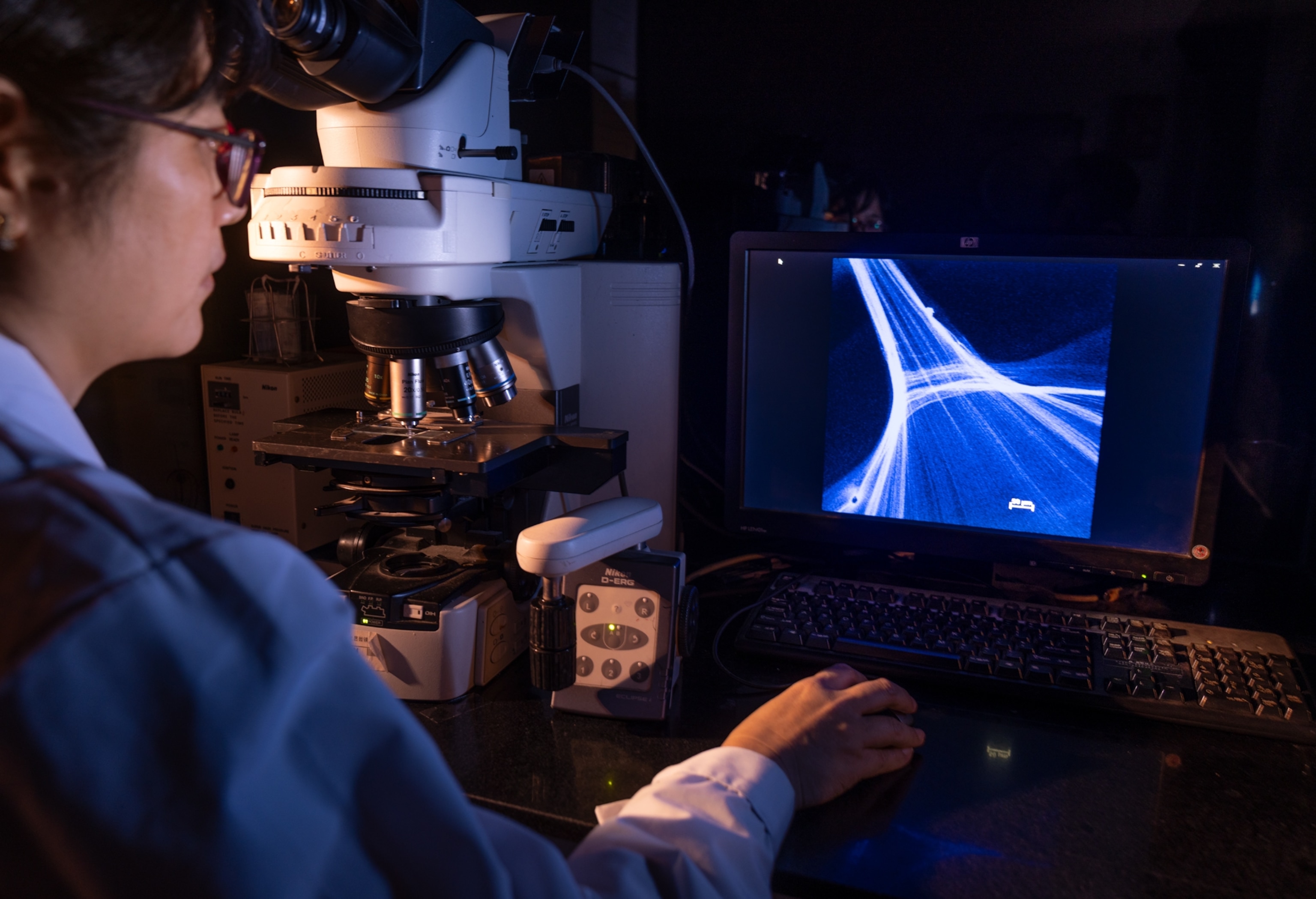 Woman looking at the monitor of the electronic microscope.