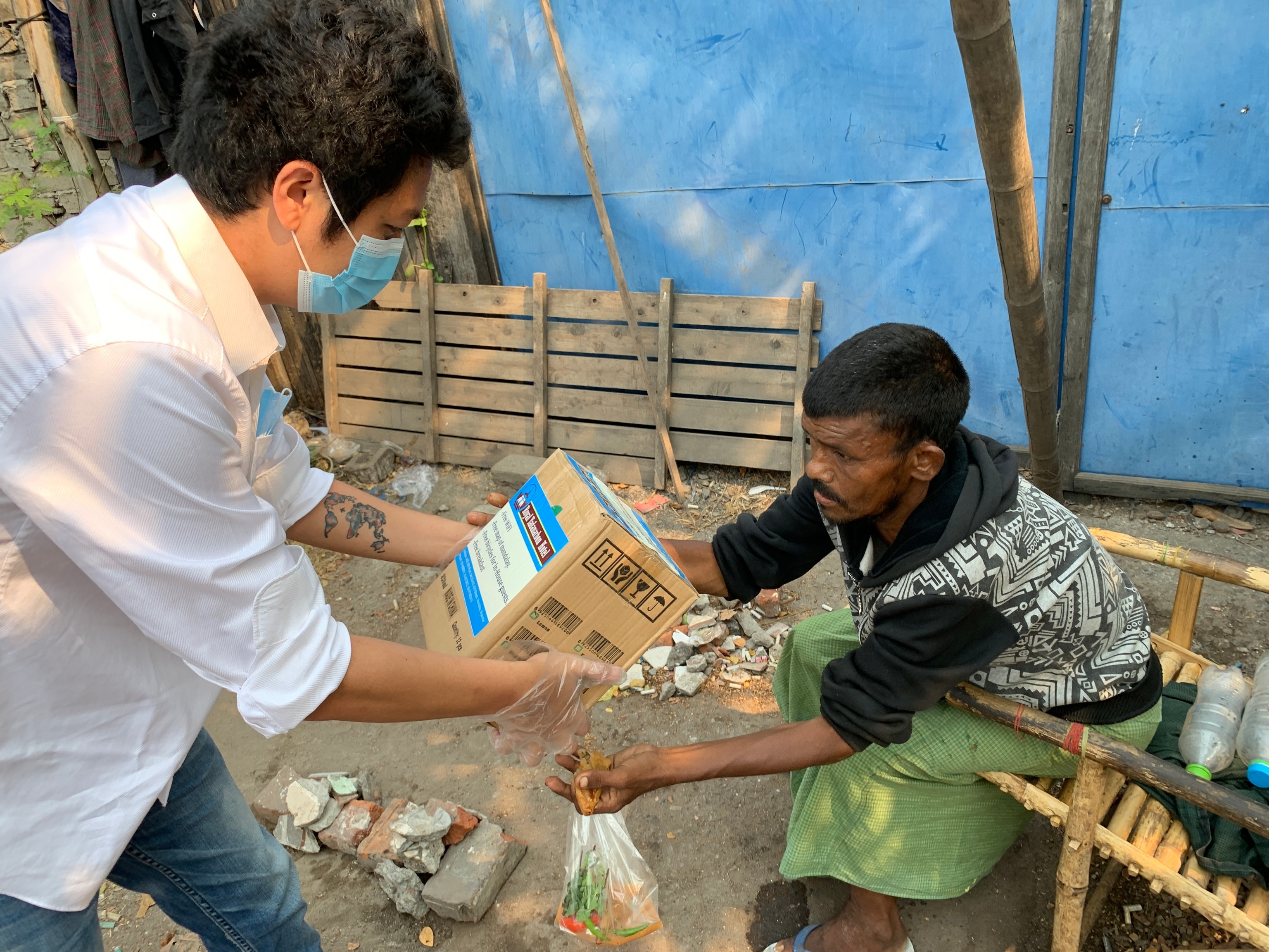 Small business owner Aung Ko Ko (left) distributes food packages to homeless people in his city of Mandalay, Myanmar. Here Salopek paused the walk in 2020 because of the COVID-19 pandemic.