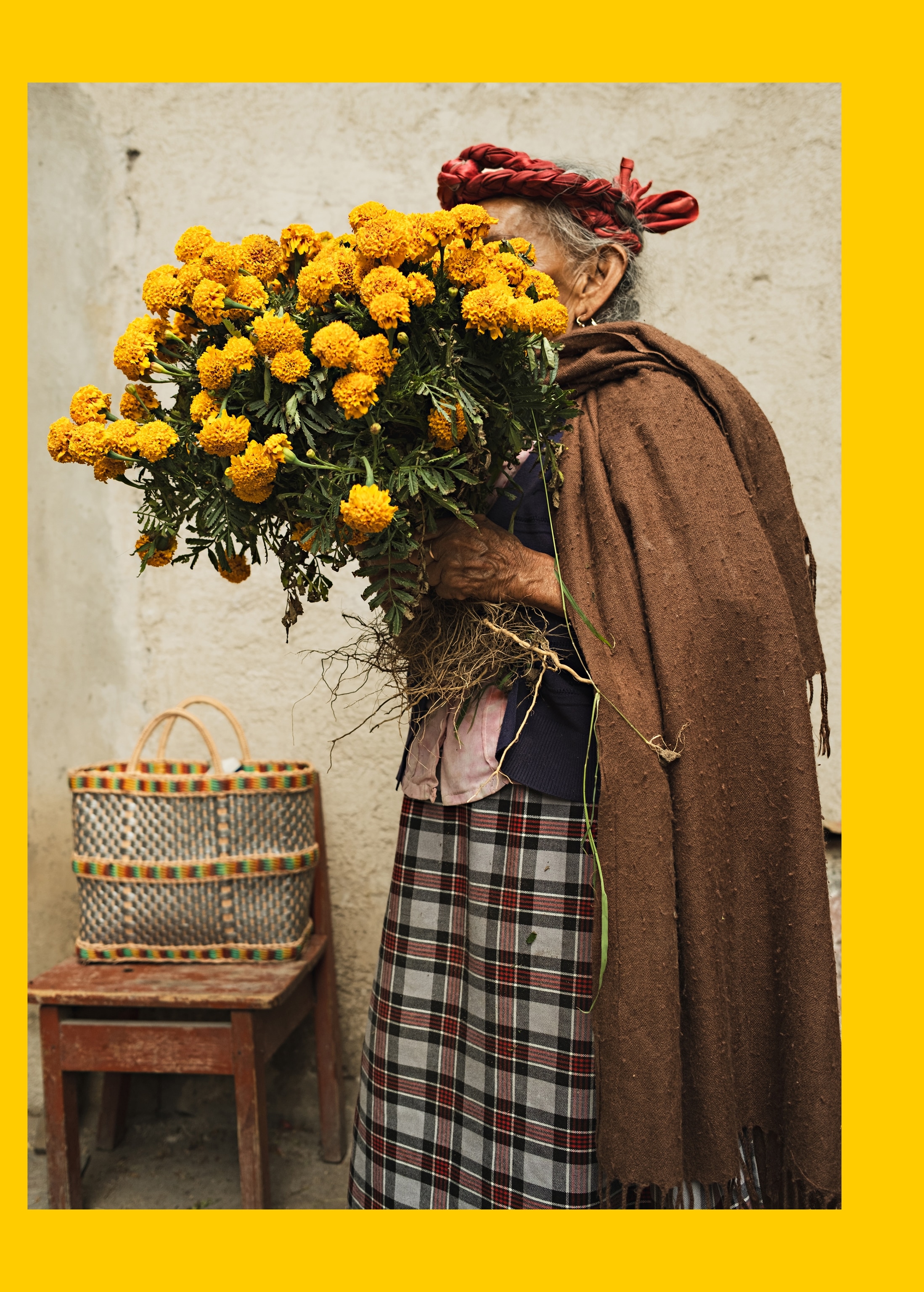 An elderly woman walking with yellow flowers over her face.
