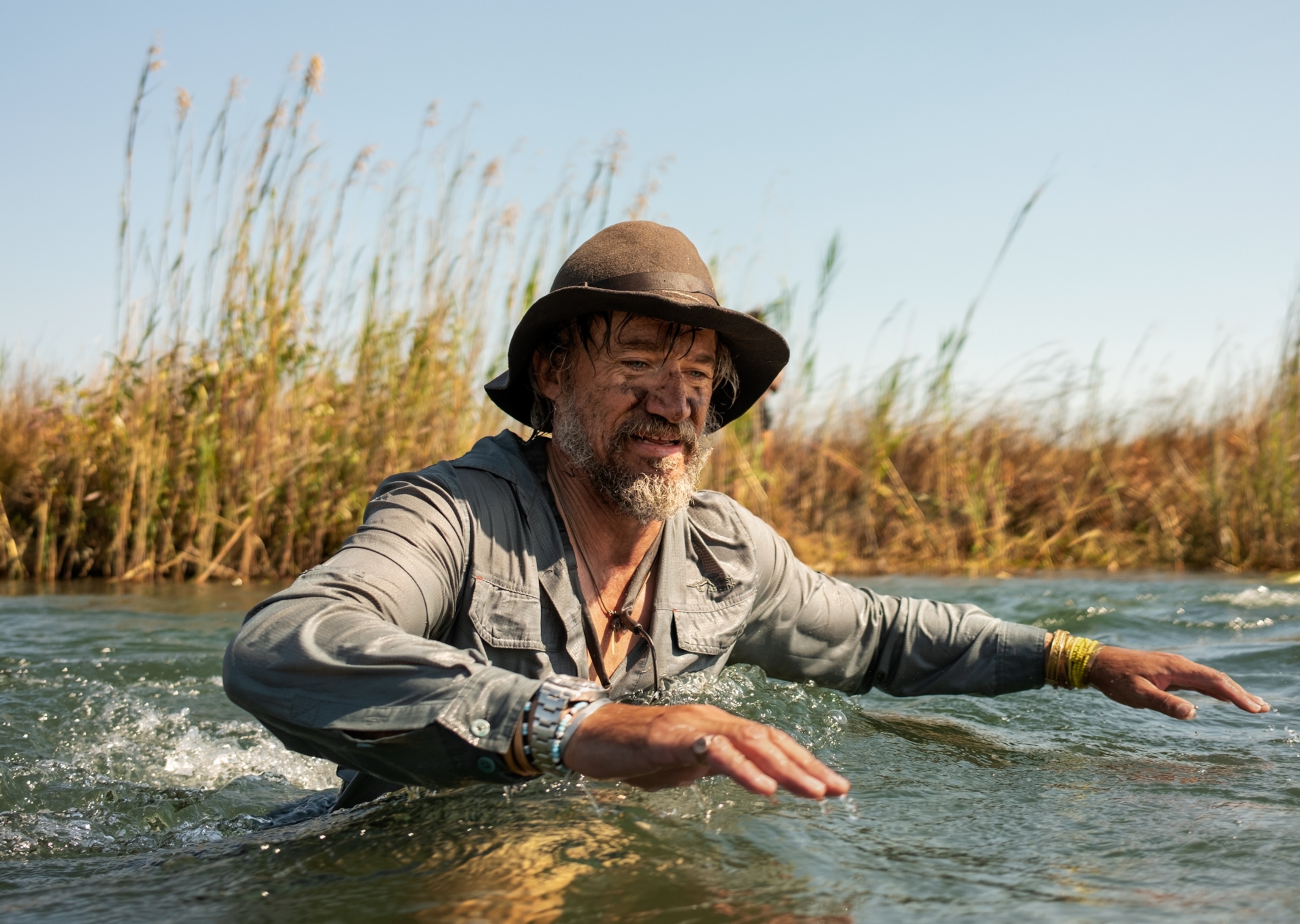 Man wading in water up to his chest.